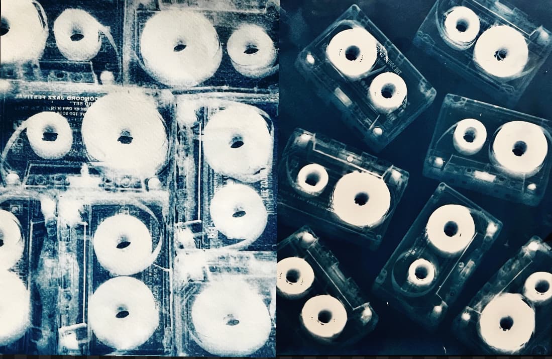 Blue-toned photographic composition of cassette tapes arranged in a grid pattern, highlighting the circular reels and creating a rhythmic visual pattern with high contrast between white circles and deep blue background.