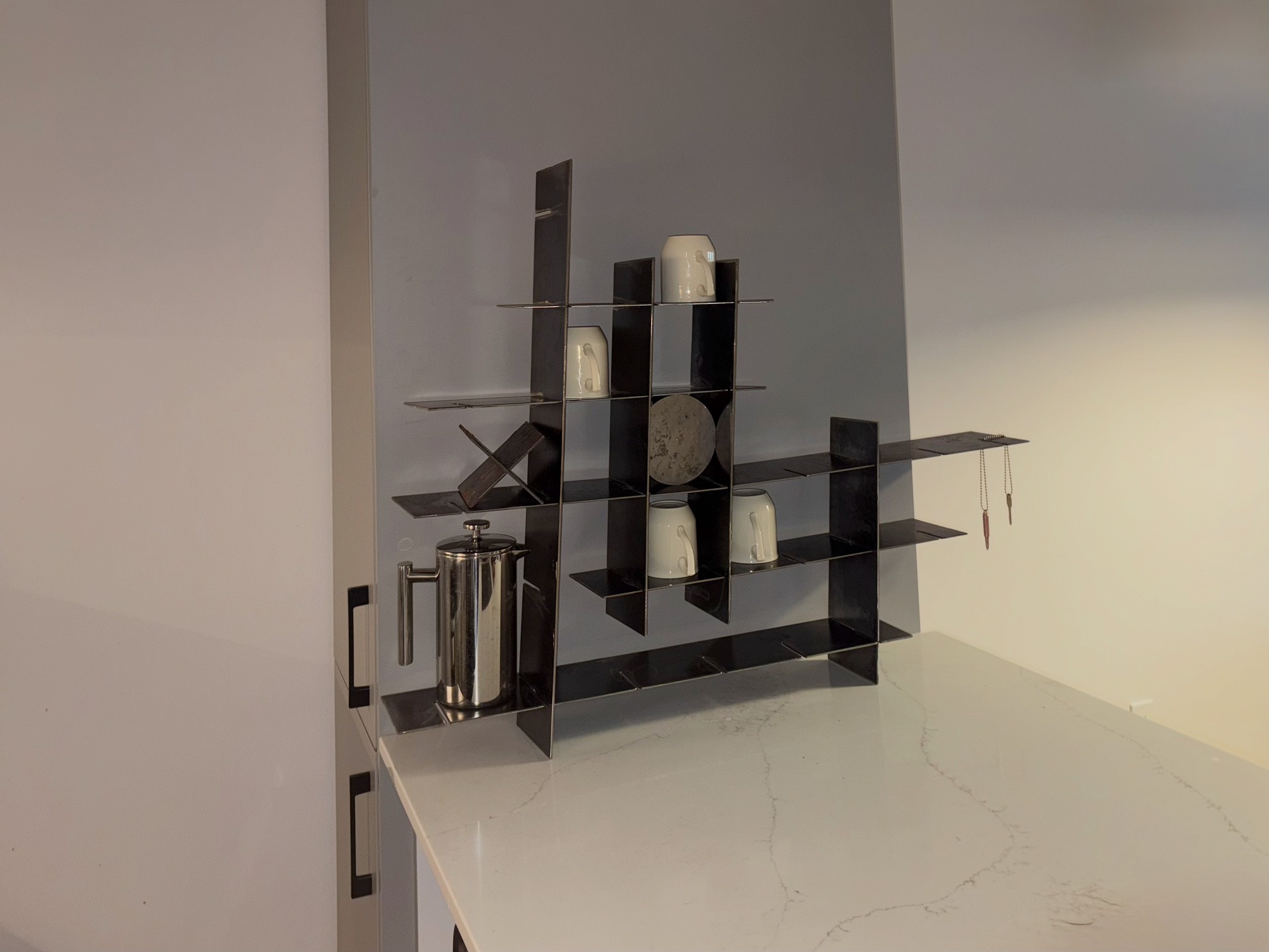 Black metal modular shelving system from different angle, emphasizing geometric structure and clean lines with same curated objects arranged on multiple levels